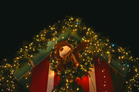 Felt bear hanging on festive fir tree garland with warm yellow lights at night