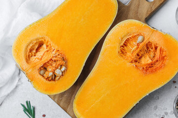 Fresh cut butternut squash with seeds and herbs on a wood cutting board, bright and clean