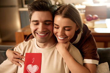 Happy couple celebrating Valentine's Day at home with greeting card