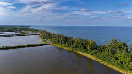 Drone shot of large aquaculture ponds bordering the tropical ocean.