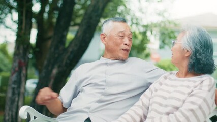 Cheerful Elderly couple Asian Mature family husband and wife talking, relaxing together sit on bench outdoors. Happy Elderly retirement couple enjoy romantic moment together in park. - Powered by Adobe