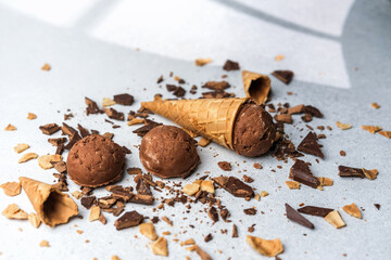 Chocolate ice cream scoops with waffle cones and chocolate chunks on light background