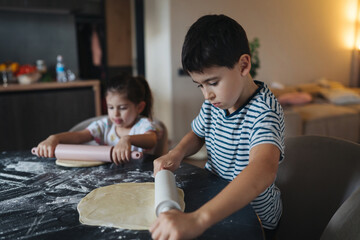 kids baking together happily, brothers and sisters skillfully kneading dough with concentration and...