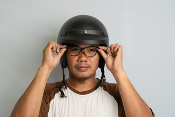 Man Wearing Helmet and Glasses Preparing for Motorcycle Ride With Neutral Background