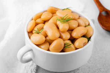 Butter beans with dill in ceramic bowl on white towel background for comfort food, nutrition or healthy meal concept