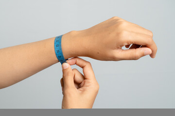 Person Adjusting A Blue Printed Wristband On Their Arm In A Studio Setting