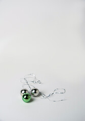 Obraz premium Green and silver Christmas tree balls and tinsel on a white background, space for text