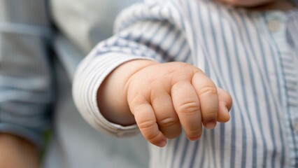 A close-up of a baby's hand reaching out, conveying innocence and curiosity, with soft textures and gentle colors.