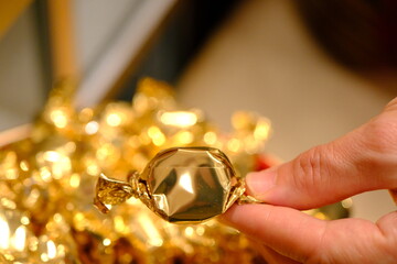 Close-up of a woman's hand holding a golden package of Eid candy. Eid Ul Fitr. Eid Al Adha. Muslim, Islam. Traditional Turkish culture. Candies sold in a candy store.

