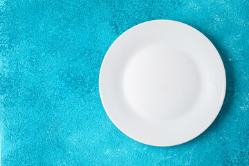 empty white ceramic plate on blue textured background