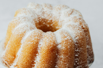 Golden bundt cake close  up on white stand with white stone background
