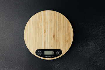 Modern wooden kitchen scale on dark stone background