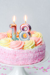 Pink-frosted birthday cake with candles for a special milestone