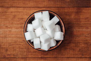Sugar cubes in a rustic bowl on a wooden table for culinary use