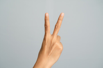 Close Up Of A Hand Showing The Number Two With Two Fingers Raised Against A Plain Gray Background
