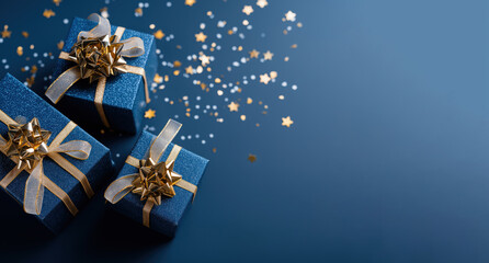 Top view of blue gift boxes with gold ribbons and sparkling stars on blue background, festive banner design