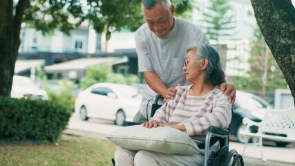Asian Elderly Married couple relaxing outdoor, enjoying retirement bonding together in park. Asian mature man husband taking care his wife sitting on wheelchair spending time together outdoors. - Powered by Adobe