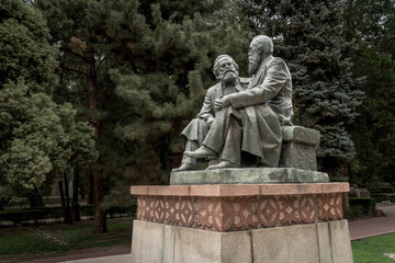Fototapeta premium Karl Marx and Friedrich Engels monument sits in Bishkek’s central park, symbolizing Soviet socialist ideology amid leafy Kyrgyz city surroundings. 