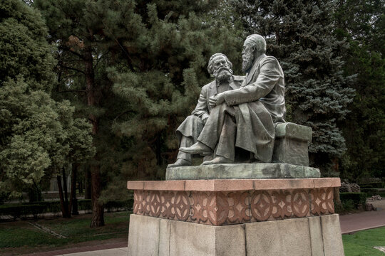 Karl Marx and Friedrich Engels monument sits in Bishkek&rsquo;s central park, symbolizing Soviet socialist ideology amid leafy Kyrgyz city surroundings.
