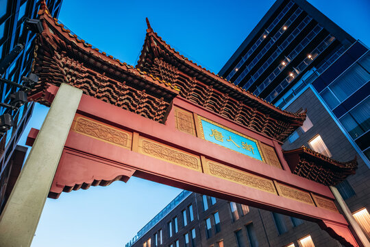 Montreal, Canada &ndash; August 13, 2025: Evening view of the illuminated Chinatown gate with people crossing the street in downtown Montreal
