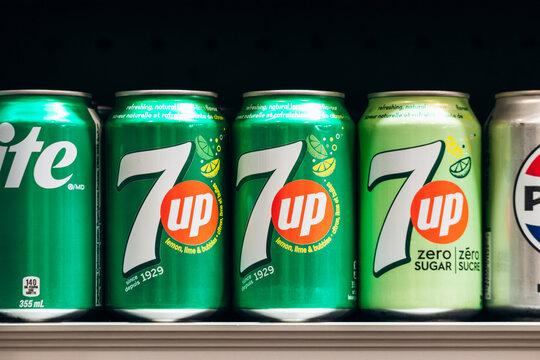 Montreal, Canada - August 14, 2025: A close-up view of 7UP soda cans displayed on a supermarket shelf in downtown Montreal, showing different varieties and bright green packaging.