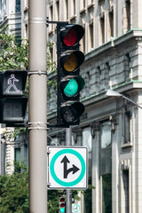Traffic light and road sign for left and right turn in downtown Montreal with historic building