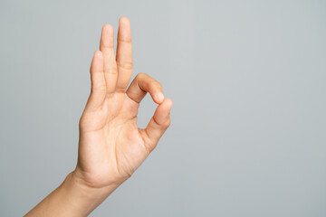 Human Hand Showing OK Gesture Sign With Thumb And Index Finger Forming Circle Against Gray Backdrop