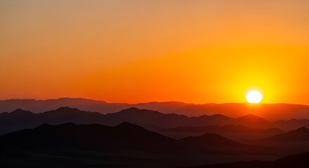 Sunset over mountain range with vibrant orange sky and silhouette