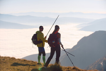 Two hikers enjoy dramatic mountain views during early morning trek above a sea of clouds