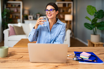 Healthcare professional conducts telemedicine session on laptop reviewing patient paperwork and typing notes while a stethoscope lies on the desk conveying trust competence reassuring positive energy
