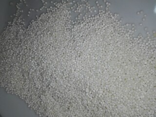 Raw white sago pearls (tapioca balls) displayed as a texture or in a heap, representing a starchy ingredient for traditional Asian puddings and desserts.