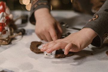 Close-up view of a child’s hands cutting out Christmas cookies from rolled dough using festive cookie cutters. A warm, cozy holiday baking atmosphere perfect for Christmas, winter, family activities