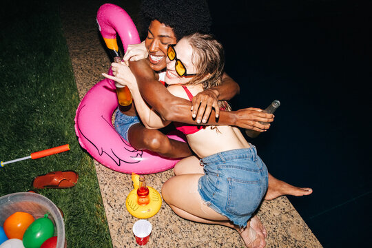Two friends hug at pool party inflatable flamingo