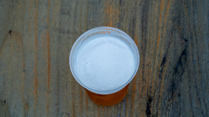 Top view of plastic cup of beer on wooden table