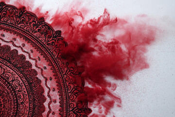 Decorative red powder mandala captured in a dynamic explosion of pigment. Vibrant, abstract composition with swirling particles and intricate circular patterns. Perfect for design and creative project