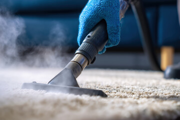 Close-up, a hand in a blue glove cleans a white shaggy rug with a steam cleaner nozzle. Efficient carpet sanitation. Professional hygiene service.