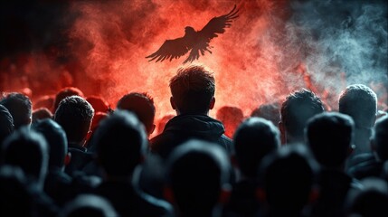 A group of people, seen from behind, looking up at a silhouette of a bird flying against a backdrop of red and blue smoke. The lighting is dramatic and moody.