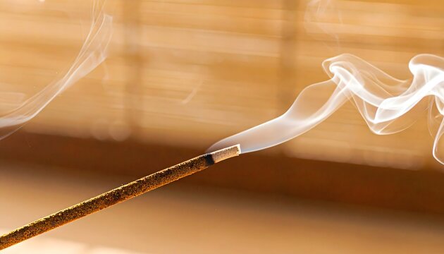 Varilla de incienso encendida con humo suave sobre fondo c&aacute;lido y desenfocado en ambiente relajante