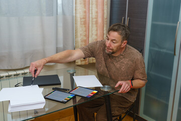 Creative man working on a digital illustration. Designer using a stylus and graphics tablet at home