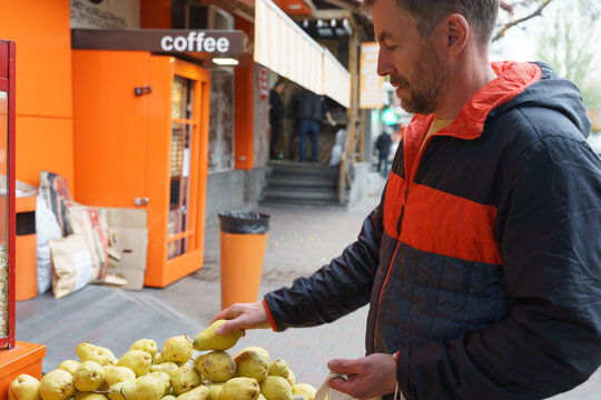 Man choosing fresh pears at an outdoor street market. Healthy food shopping in the city