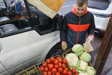 Man buying fresh vegetables at an outdoor street market. Customer choosing produce from a vendor's van