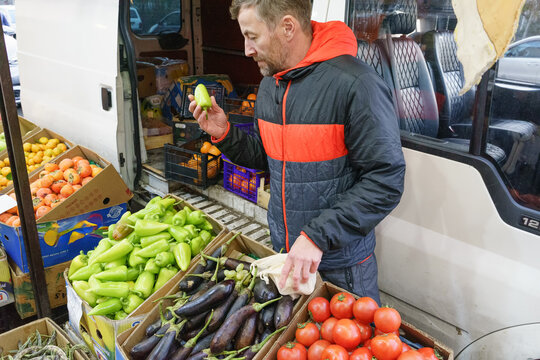 Man shopping for fresh vegetables at an outdoor market. Customer choosing local produce from a van
