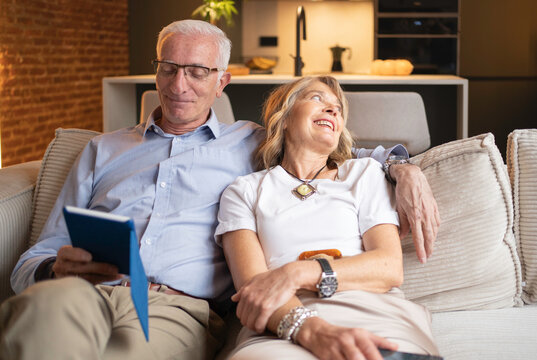 Senior couple enjoying time together on the sofa, man using a tablet