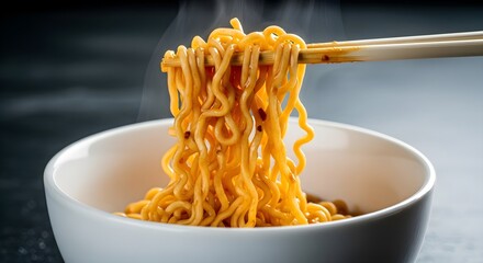 Steaming hot instant noodles being lifted from a white bowl with chopsticks against a dark background concept of quick meal preparation