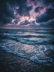 Obraz premium Majestic Ocean Waves Crash Against the Shore Under a Dramatic Sky at Twilight Near a Coastal Beach