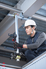 天井が近い高所の足場で単管パイプを固定するクランプなどの施工作業　鳶職や作業員のイメージ　レンチで締め