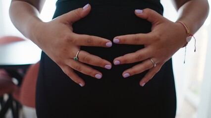 Pregnant woman holding her belly, showing maternal care and loving connection