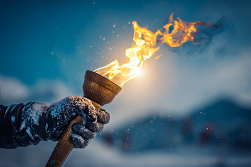 Flame ignites from a torch held by a gloved hand in a snowy mountain landscape during twilight hours