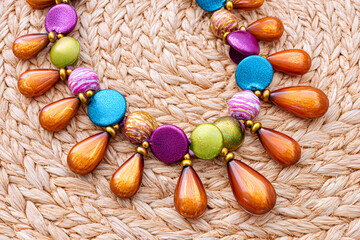 Colorful beaded necklace displayed on woven surface with vibrant shapes and textures
