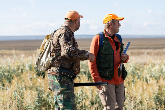 A hunters with a gun in camouflage clothing. A senior man with a gun, medium shot, searching for game. - Powered by Adobe